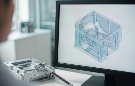 Design engineer reviewing a 3D CAD model of an injection molded plastic part with uniform wall thickness, ribs and draft angles on a computer monitor