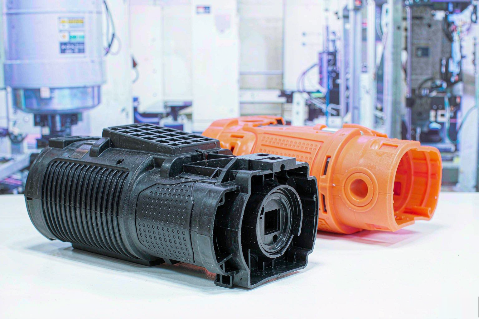 Injection molded power tool housings in black and orange on a workbench
