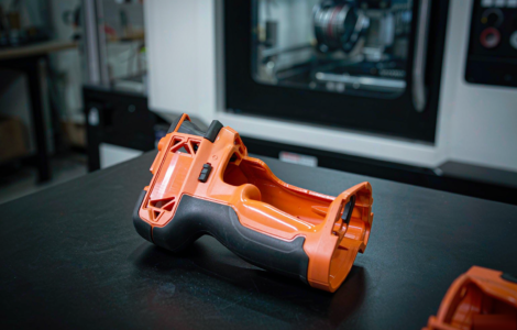 Two-shot injection molding: power tool housing with rigid orange ABS body and soft black TPE overmolded grip