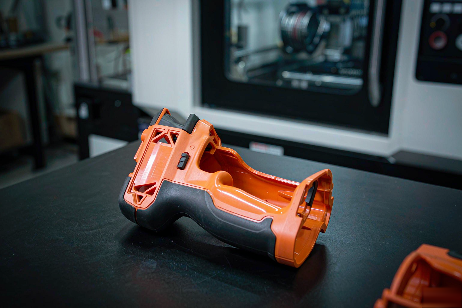 Two-shot injection molded power tool housing with rigid orange ABS body and soft black TPE grip